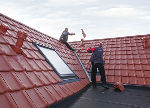 Dachdeckermeister und Dachdeckergeselle arbeiten auf dem Dach.